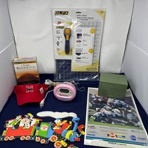 Lot #221 - Crafting and Collectibles Lot - OLFA Rotary Cutter, Nebraska Cap, and More.