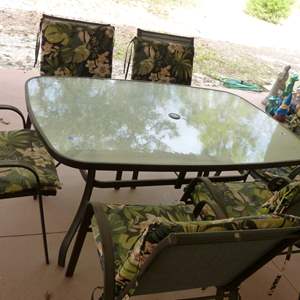 Lot #400   Patio 6 chair-glass top table and cushions (needs a good cleaning)